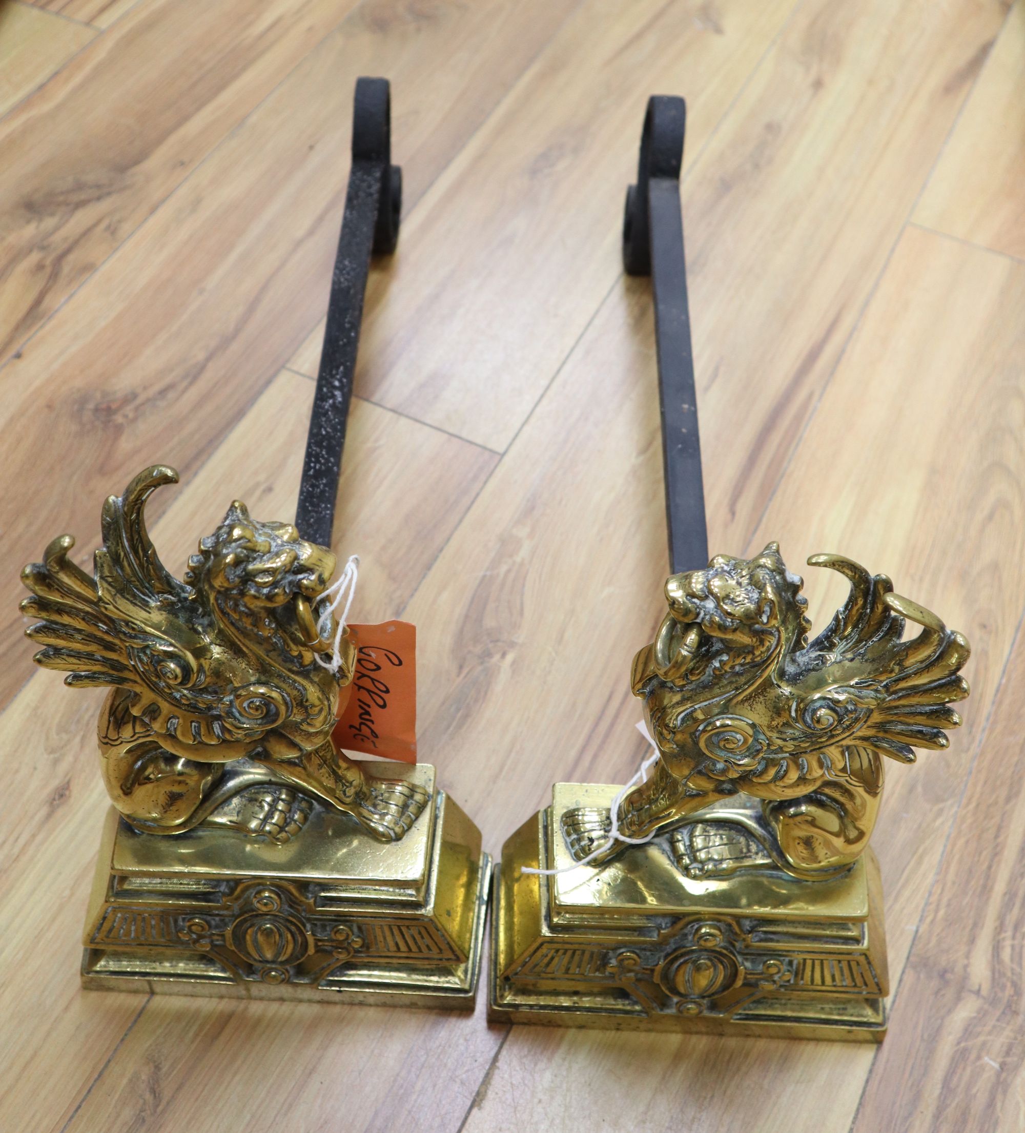 A pair of Victorian cast brass winged lion fire dogs, depth 53cm height 31cm